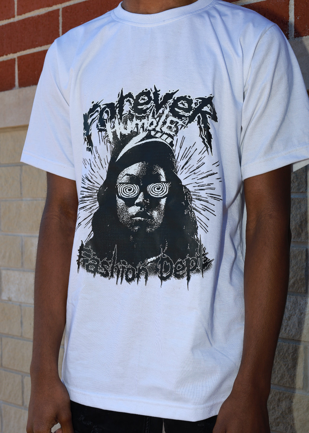 Person wearing a white t-shirt with a graphic design of a person in a crown and sunglasses, with text 'Fashion Doll'.